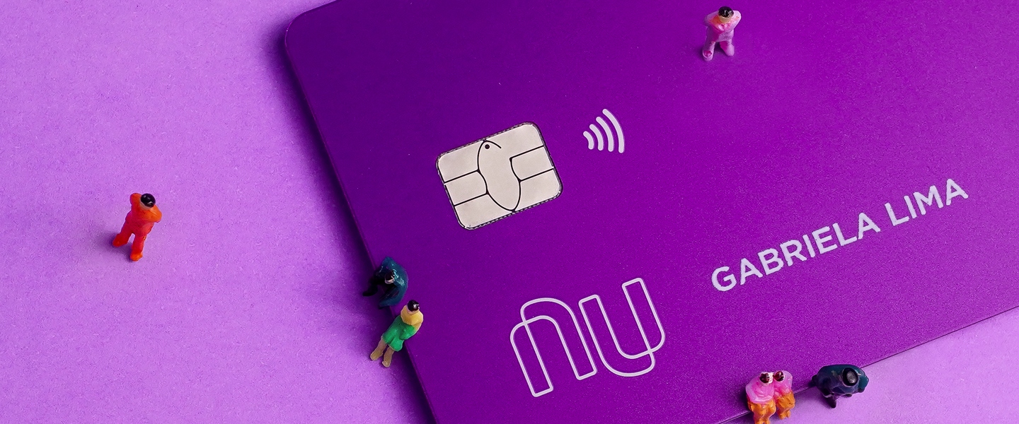 Little toy figures around Nubank's purple credit card